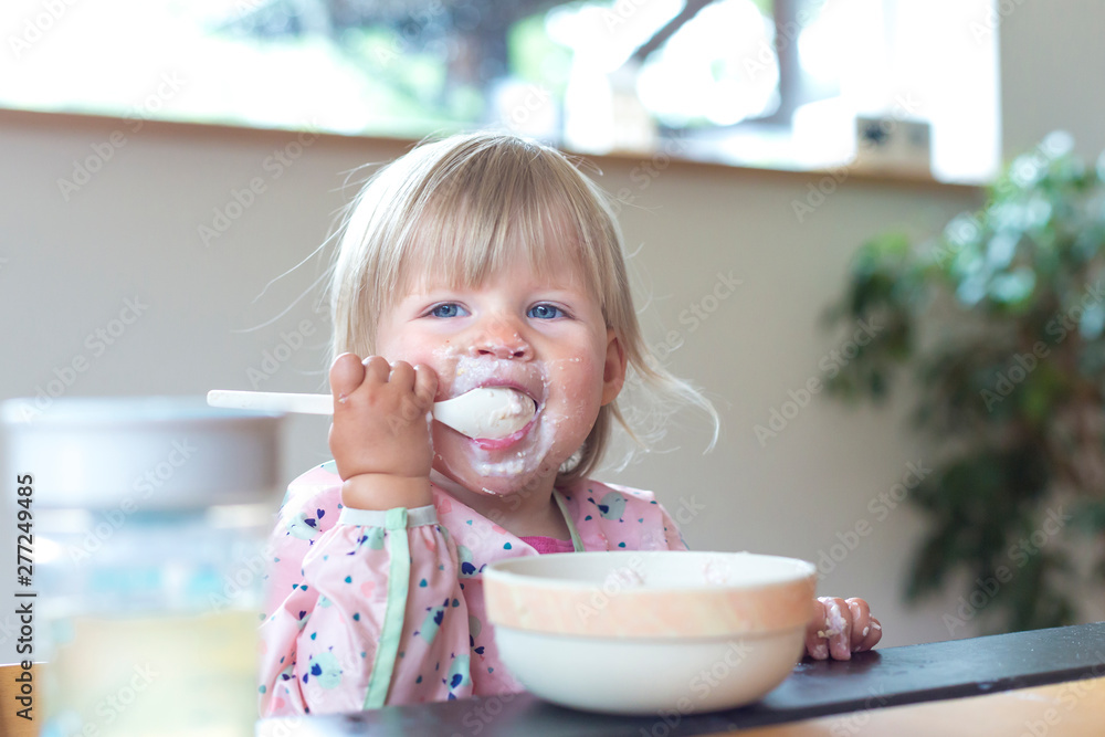 Portrait of blonde girl eating in highchair Portrait of blonde girl eating in highchair