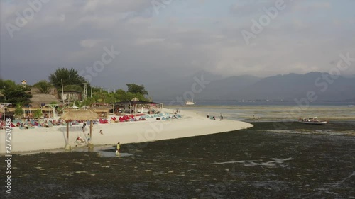 Aerial view of white sandy beach, resort and touists swinging at seashore at low tide. Gili Air island, Indonesia photo