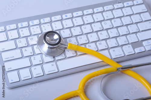 A medical stethoscope near a laptop on a wooden table