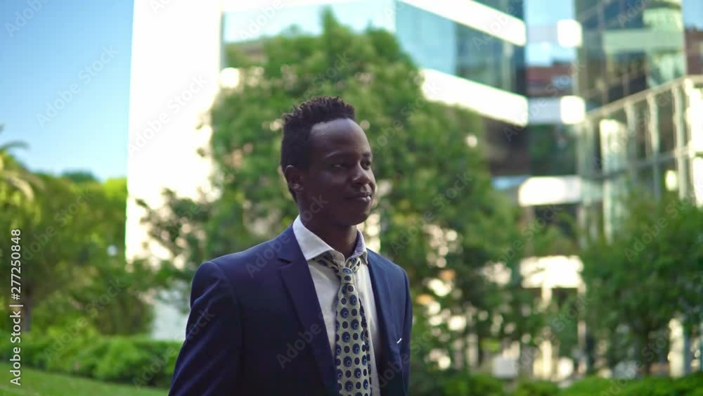 African American businessman wearing blue suit walking near office. Business concept African American businessman wearing blue suit walking near office. Business concept