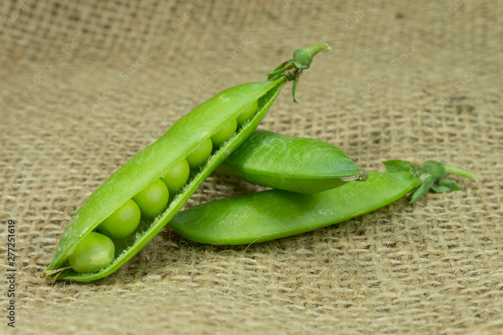 Fresh green pea pods on brown jute background Fresh green pea pods on brown jute background