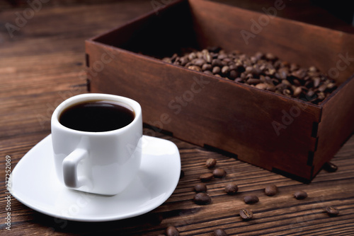 white coffee cup, morning side light coffee beans wooden coffee box, natural wooden background