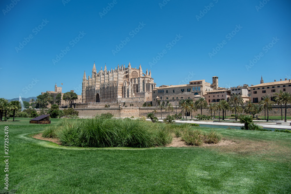 Majorca 2019: Cathedral La Seu of Palma de Mallorca on a sunny summer day with blue sky. Image composition with grass in the foreground