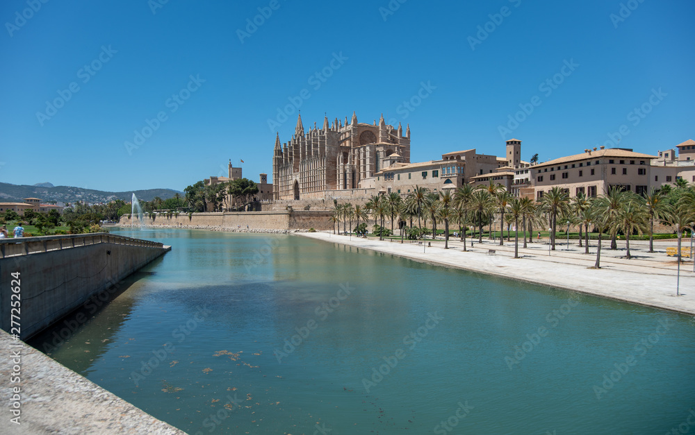 Majorca 2019: Panoramic view of Cathedral La Seu of Palma de Mallorca on a sunny summer day with blue sky. Image composition with lake in the foreground