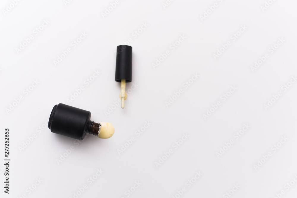 Fototapeta premium yellow gel nail polish in a black bottle on a white background. Manicure concept for blogs and design templates