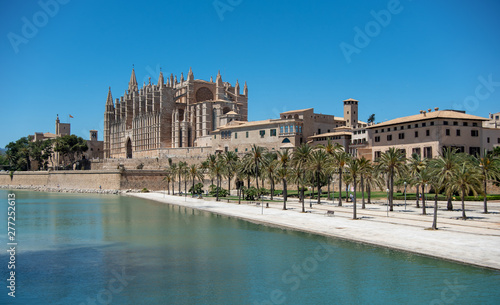 Majorca 2019  Cathedral La Seu of Palma de Mallorca on a sunny summer day with blue sky. Image composition with lake and palm trees in the foreground