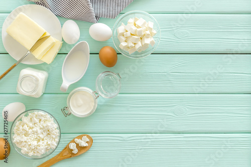 Fresh dairy products with milk, cottage, eggs, butter, yougurt on mint green wooden background top view mock up
