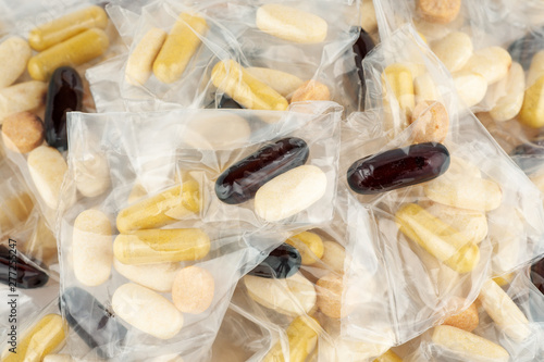 Pills dosage in plastic bag on white background, top view, macro