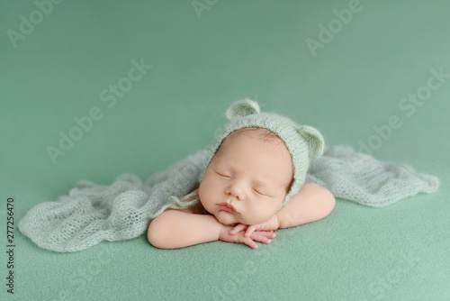 Sleeping newborn baby on a green background. Photoshoot for the newborn. A few days from birth.