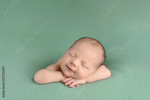 Sleeping newborn baby on a green background. Photoshoot for the newborn. A few days from birth.
