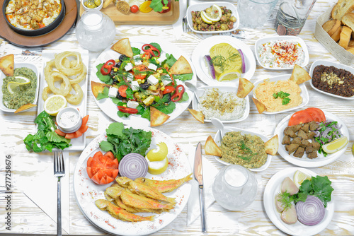 Greek food background. Meze, gyros, fried squid rings, souvlaki, uzo, fish, pita, greek salad, tzatziki, assortment of feta, olives and vegetables. Traditional different greek dishes set. photo