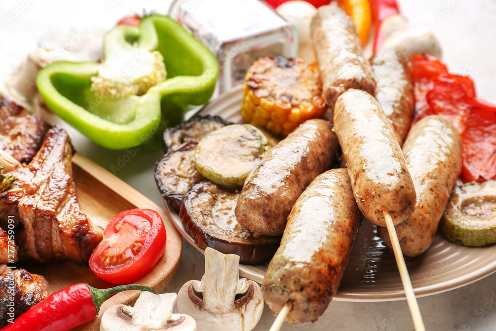 Tasty grilled meat with sausages and vegetables on table Tasty grilled meat with sausages and vegetables on table