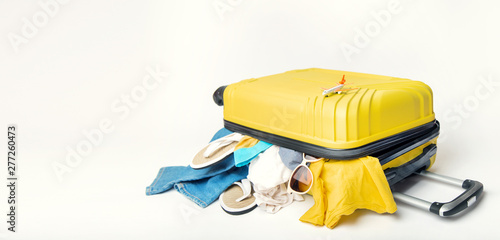 yellow suitcase with clothes of ttourist on a white background. concept quick fees late on the plane photo