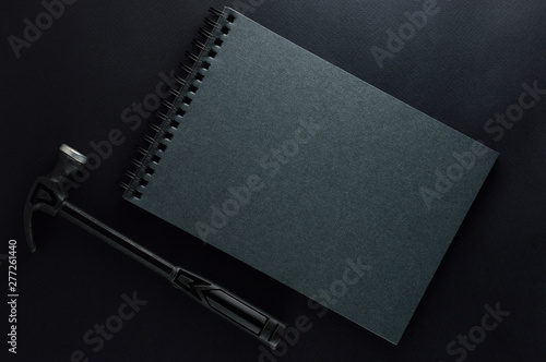 Isolated black hammer and black gray note book on black matte background