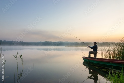 angler catching the fish during misty dawn