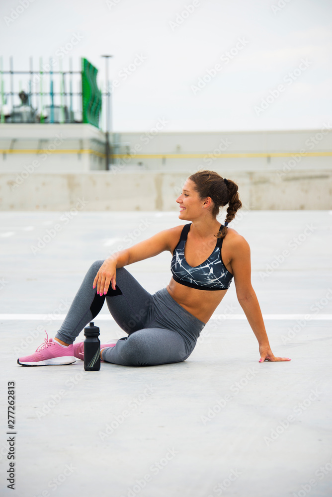 Sporty fitness girl drinking water and smiling, taking break while exercise, outdoor urban city background Sporty fitness girl drinking water and smiling, taking break while exercise, outdoor urban city background
