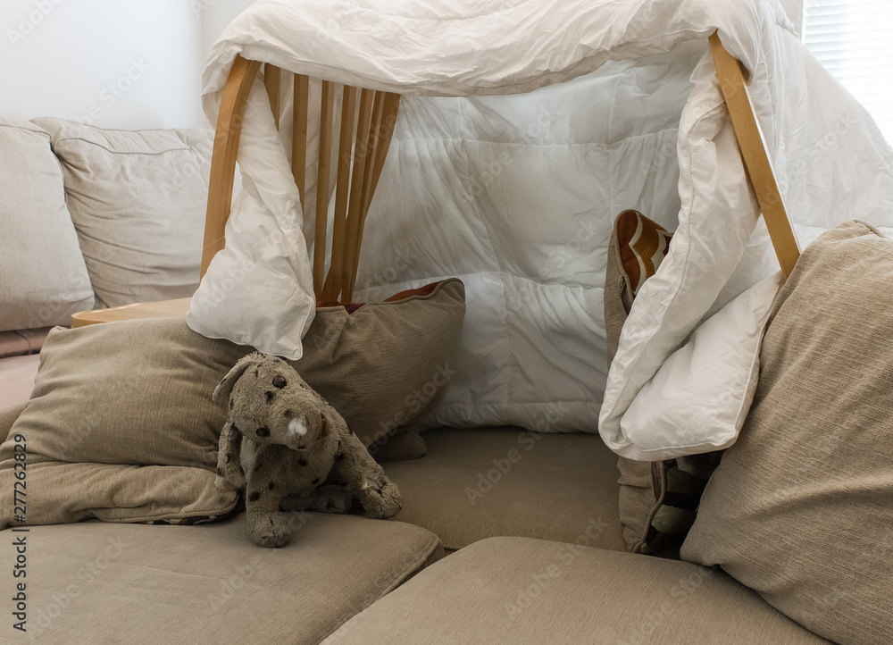 A pillow fort made of blankets chairs with a stuffed animal in the living  room. Great for kids watching movies Stock Photo | Adobe Stock