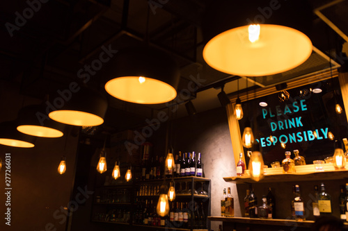 Vintage luxury interior lighting decor at Restaurant, cafe or bar. old Vintage light bulb lamps. Restaurant Bar or Cafe interior design. Vintage Light bulbs  in front of alcoholic drinks bottles shelf © Hakan Tanak