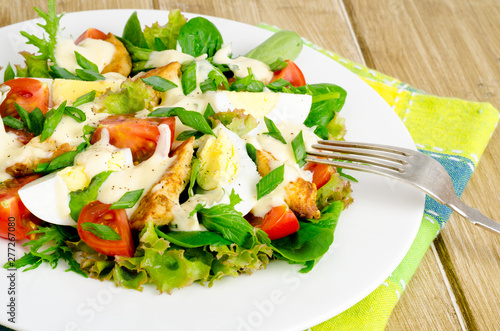 Salad of fresh vegetables, eggs, chicken meat with white sauce.