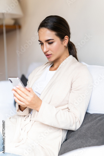 Young woman use of mobile phone and sit on sofa at home