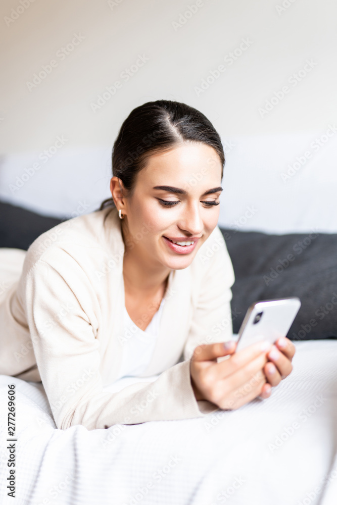 Young woman lying on the sofa while writing a text message on her cell phone Young woman lying on the sofa while writing a text message on her cell phone