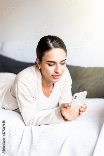 Close up of a relaxed girl using a smart phone lying on a sofa in the living room at home