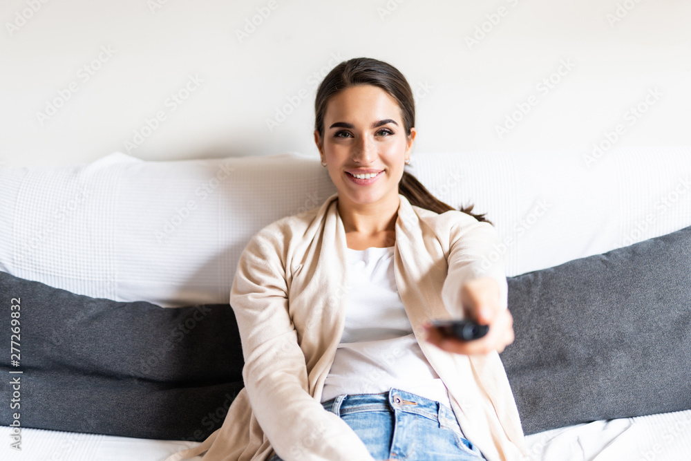 Happy young woman watching tv on sofa at home Happy young woman watching tv on sofa at home