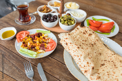 Traditional Turkish Breakfast Table. Turkish Breakfast Food Cuisine Culture. Turkish pide yufka ekmek, tea, bagel, borek, sikma, cheese, olives, oil and honey on wooden table from top view.
