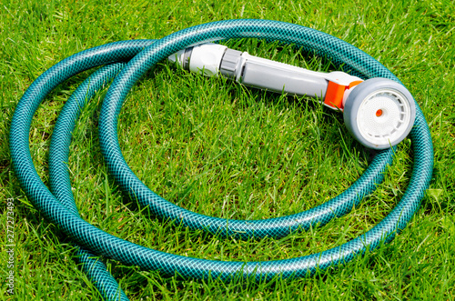 Green hose for watering lies on grass, lawn photo