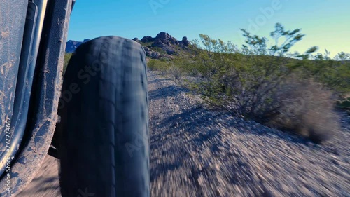 ATV Lower to Ground with Mountain. view moves down behind the front tire of an all terrain vehicle in the desert photo