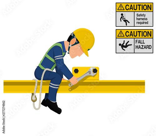 An industrial worker with safety harness is working at height