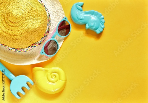 Summer holiday background for kids, vacation at sea. on the background of a straw hat, sunglasses, children's toys for the sandbox, sand molds, a children's airplane as a concept of air travel.