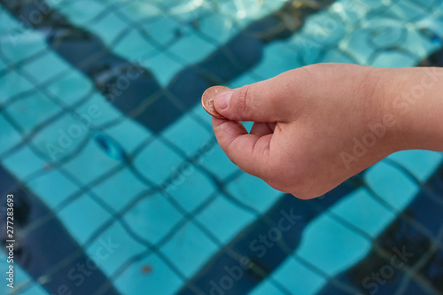 Hand holding a copper penny over a pool of water      photo