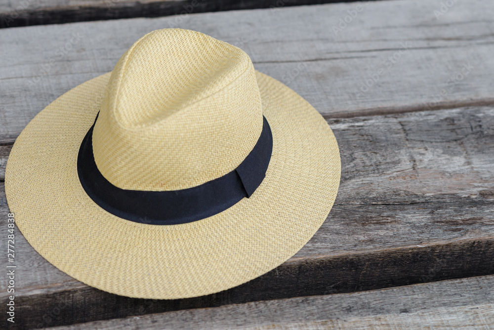 straw beach hat with black ribbon on the wooden seat wtih free space, travel summer concept