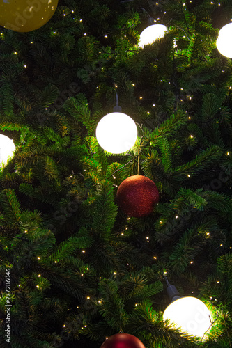 Fototapeta Naklejka Na Ścianę i Meble -  Illuminated  decoration of  Christmas tree with  hanging yellow and red ball.