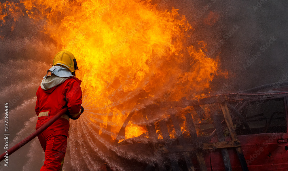 Brave firefighter using extinguisher and water from hose for fire fighting, Firefighter spraying high pressure water to fire, Firefighter training with dangerous flames, Copy space-Image Brave firefighter using extinguisher and water from hose for fire fighting, Firefighter spraying high pressure water to fire, Firefighter training with dangerous flames, Copy space-Image