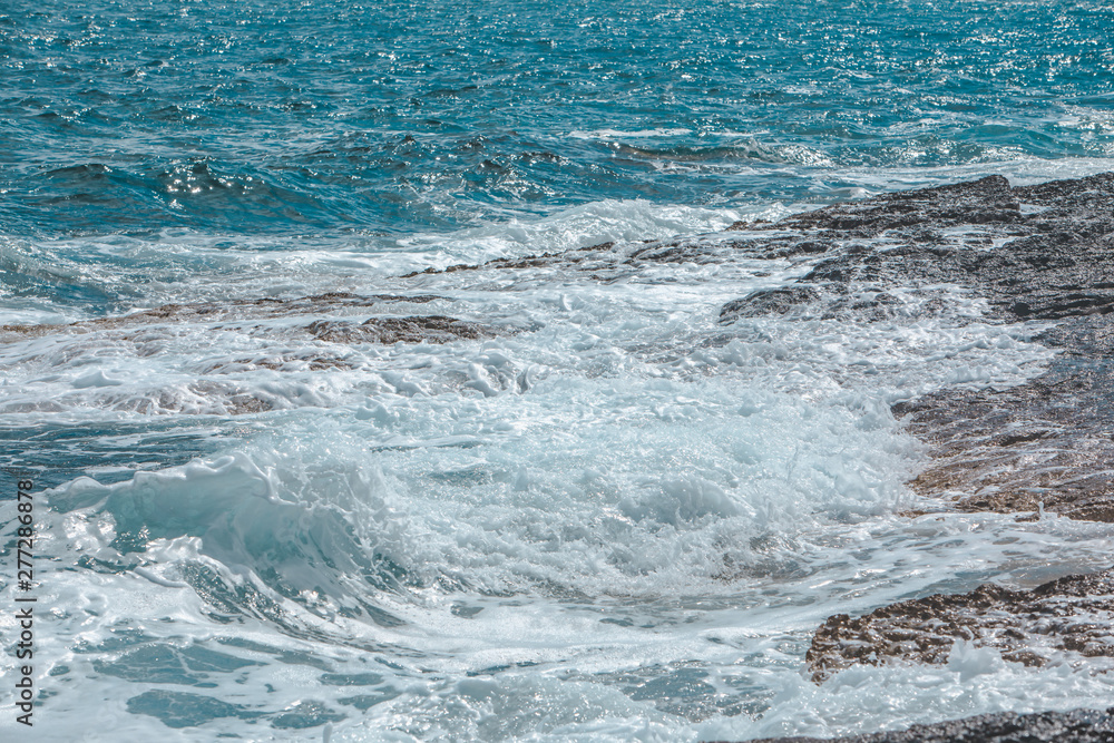 view of rocky seaside waves with white foam