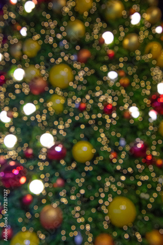 Illuminated blurred bokeh of Christmas tree decoration with hanging lights ball.