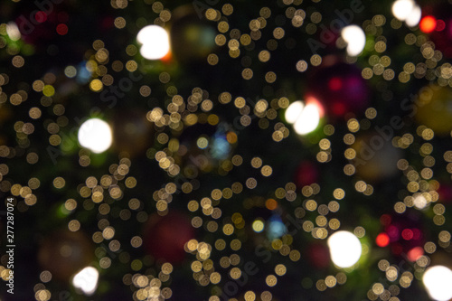 Illuminated blurred bokeh of Christmas tree decoration with hanging lights ball.