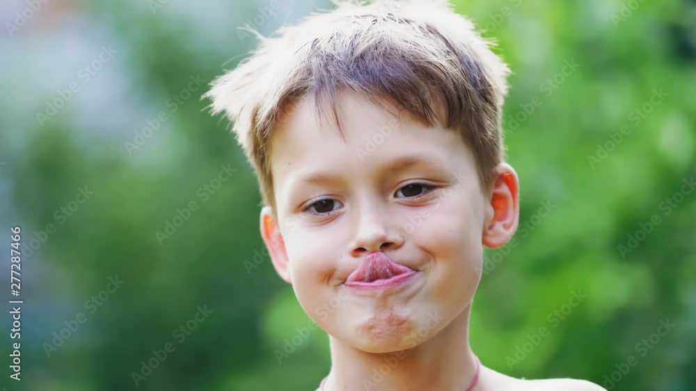Boy's face close-up. Cute little boy touches the nose by his tongue. Portrait of a child showing funny face. Boy's face close-up. Cute little boy touches the nose by his tongue. Portrait of a child showing funny face.