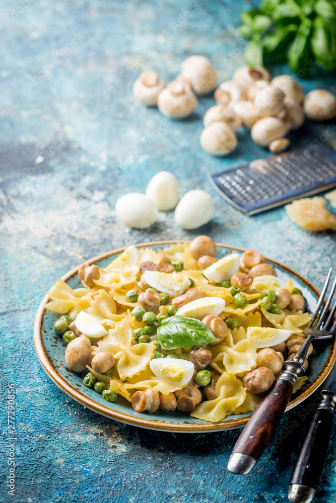 Farfalle pasta with champignon mushrooms, peas, egg and creamy sauce on a plate. Farfalle pasta with champignon mushrooms, peas, egg and creamy sauce on a plate.