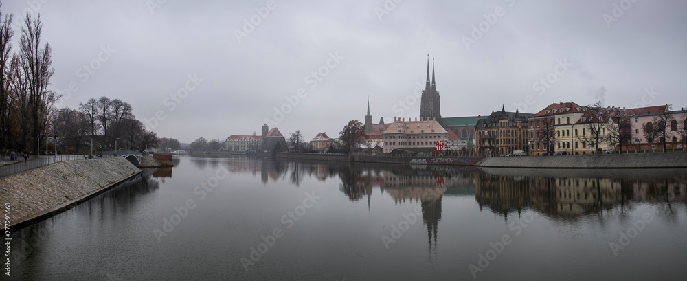 Panoramic view of the Cathedral of St. John the Baptist reflected in Oder river at cold foggy day. Ostrow Tumski district. Wroclaw. Poland