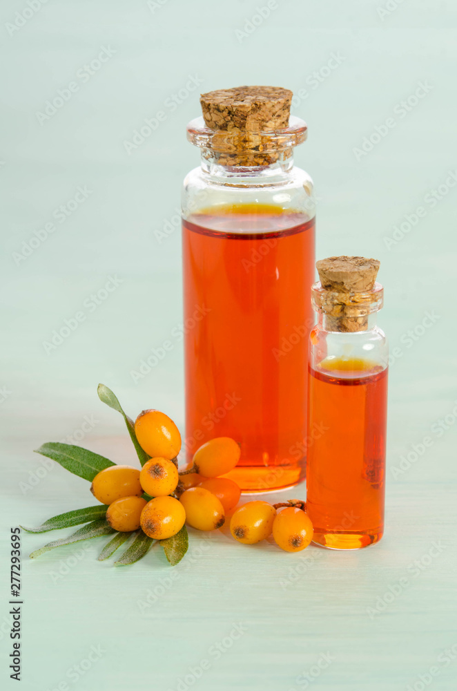 Sea buckthorn and two bottles with sea buckthorn oil on blue table Sea buckthorn and two bottles with sea buckthorn oil on blue table