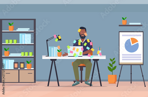 businessman covered with stick notes business planning deadline concept african american office worker using laptop sitting at workplace modern conference room interior flat full length horizontal