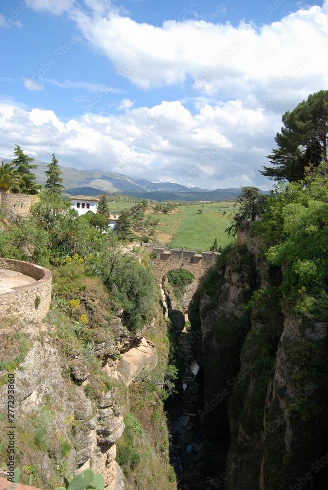 Elevated view of the old bridge crossing the ravine with views towards the countryside and mountains., Ronda, Spain.