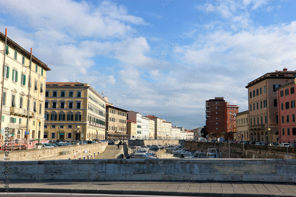 Main canal of Livorno, Italy full of boats under blue sky with clouds