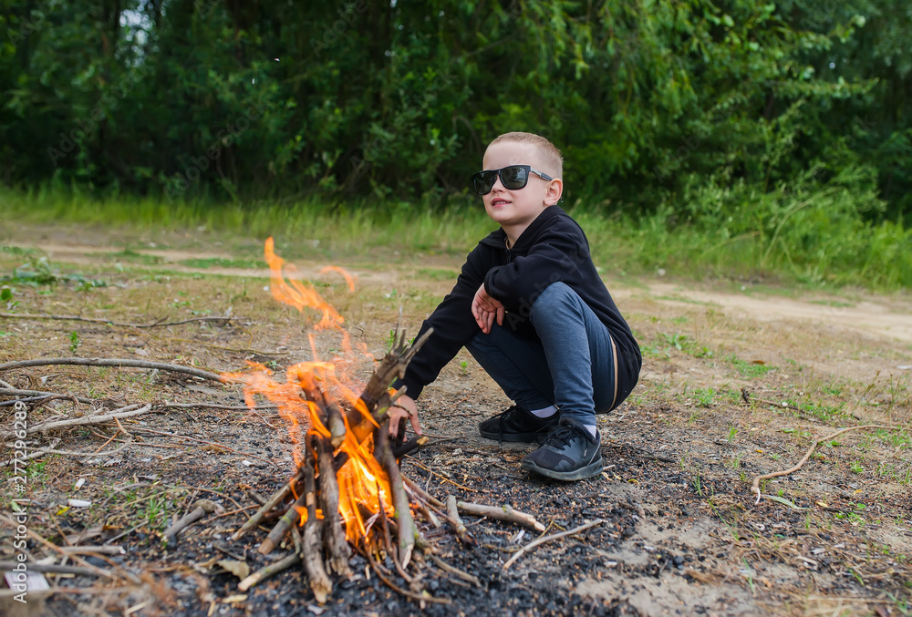 The cute sunglasses makes fire in the for cooking. Camping with in summer forest. Stock-foto | Adobe Stock