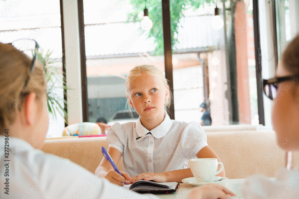girl writes in notebook wishes of the client. Children as adults at work. girl writes in notebook wishes of the client. Children as adults at work.