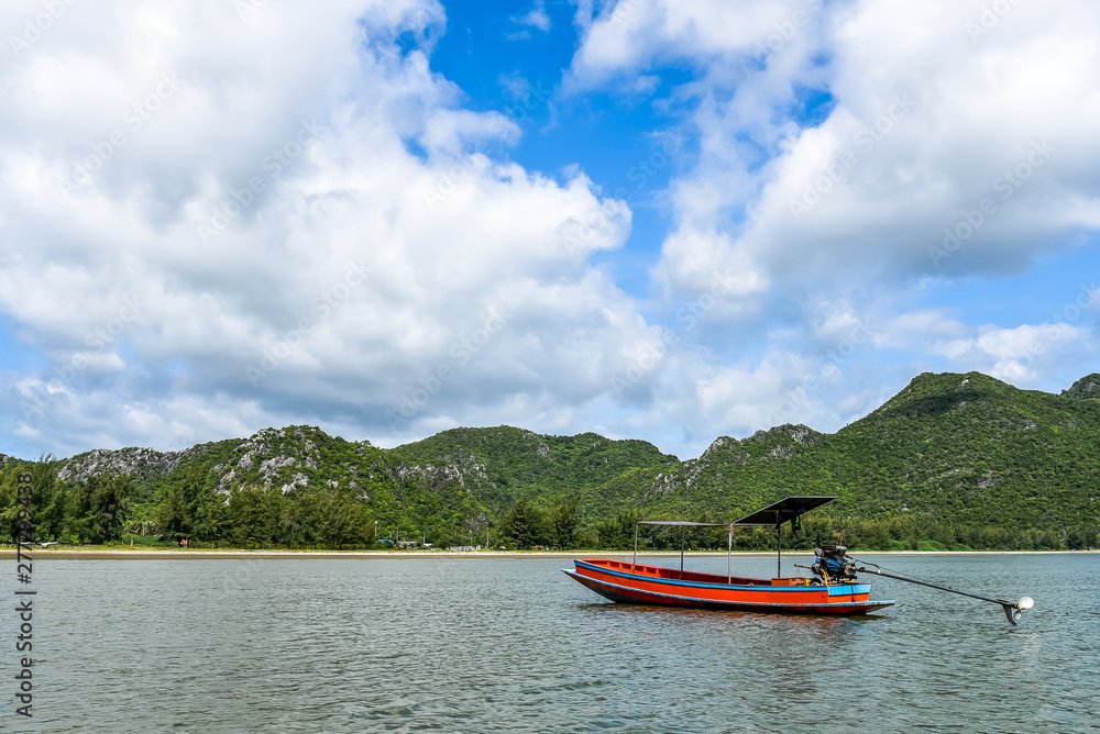 Fototapeta premium Alone fishing boats float on the sea with a blue sky and clouds background.