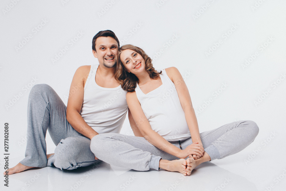 happy family engaged in recreational gymnastics. A man, a pregnant woman are sitting on the floor. Isolated on white background happy family engaged in recreational gymnastics. A man, a pregnant woman are sitting on the floor. Isolated on white background